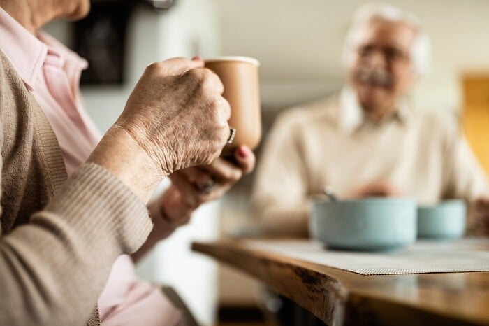 Senior woman holding coffee cup at breakfast table