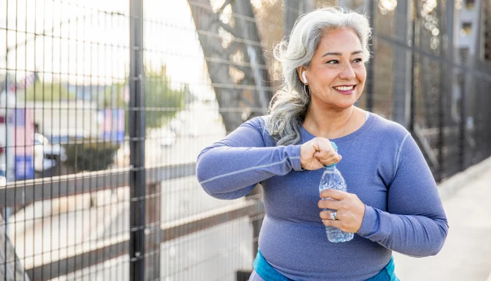 Mature woman drinking water while on a walk.