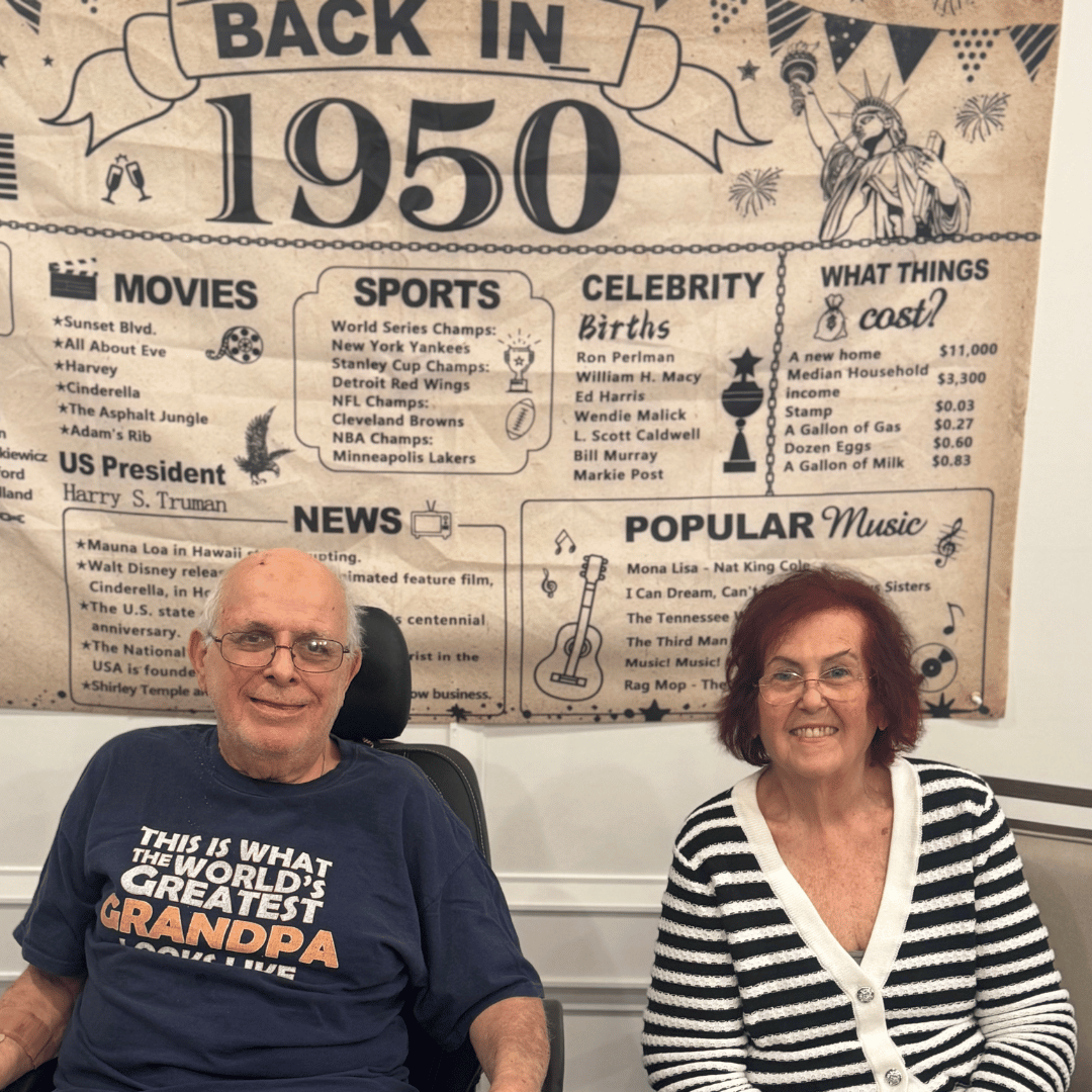 Residents of The Bristal at Waldwick smile for a photo in front of a 1950s celebratory banner